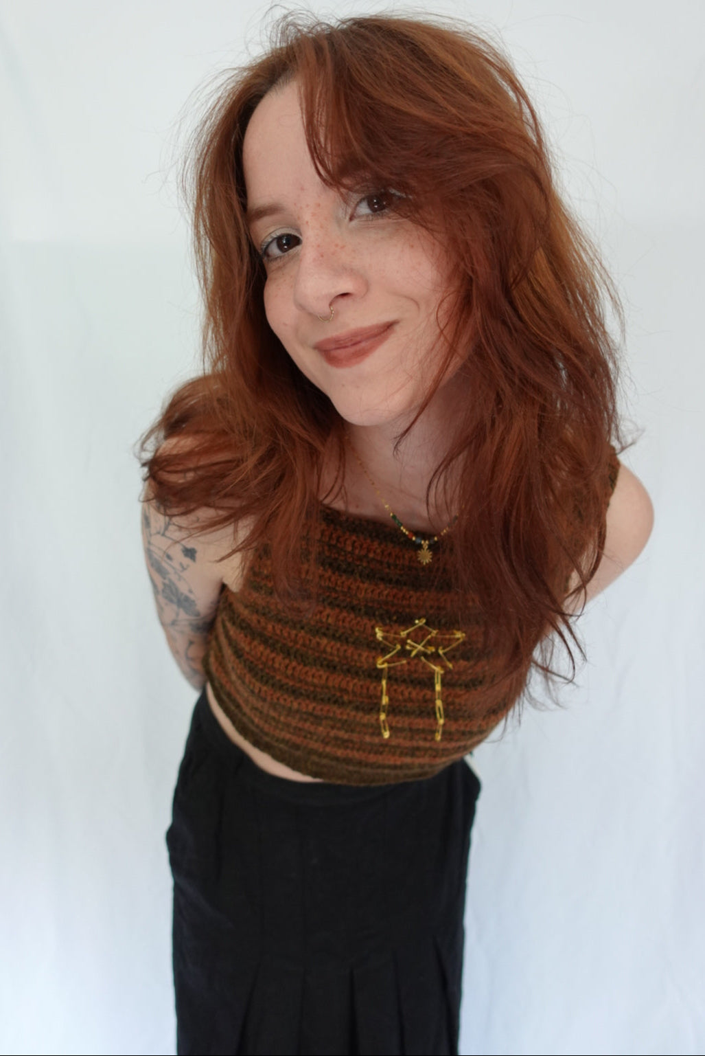Person with red hair and tattoos lying on a white surface