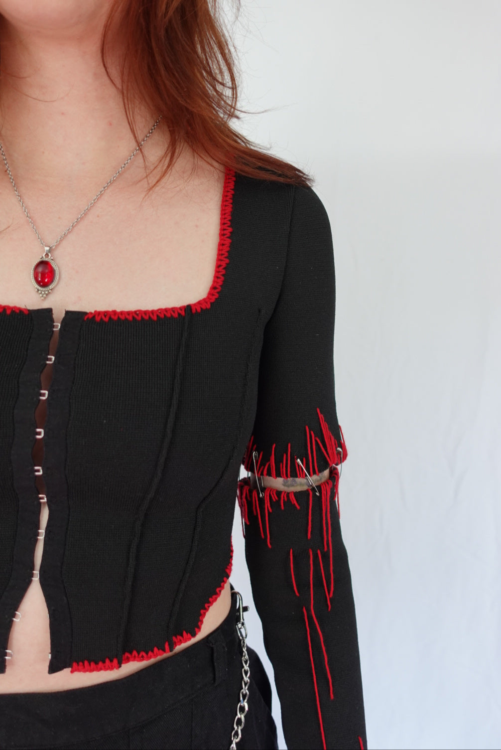 Close-up of a person wearing a black outfit with red accents on a white background