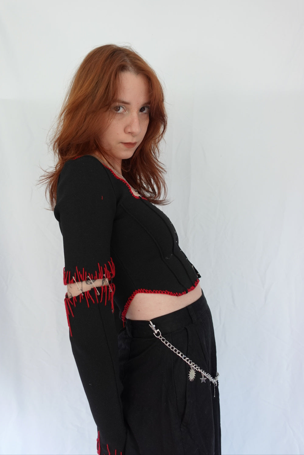 Woman wearing a black outfit with red accents against a white background
